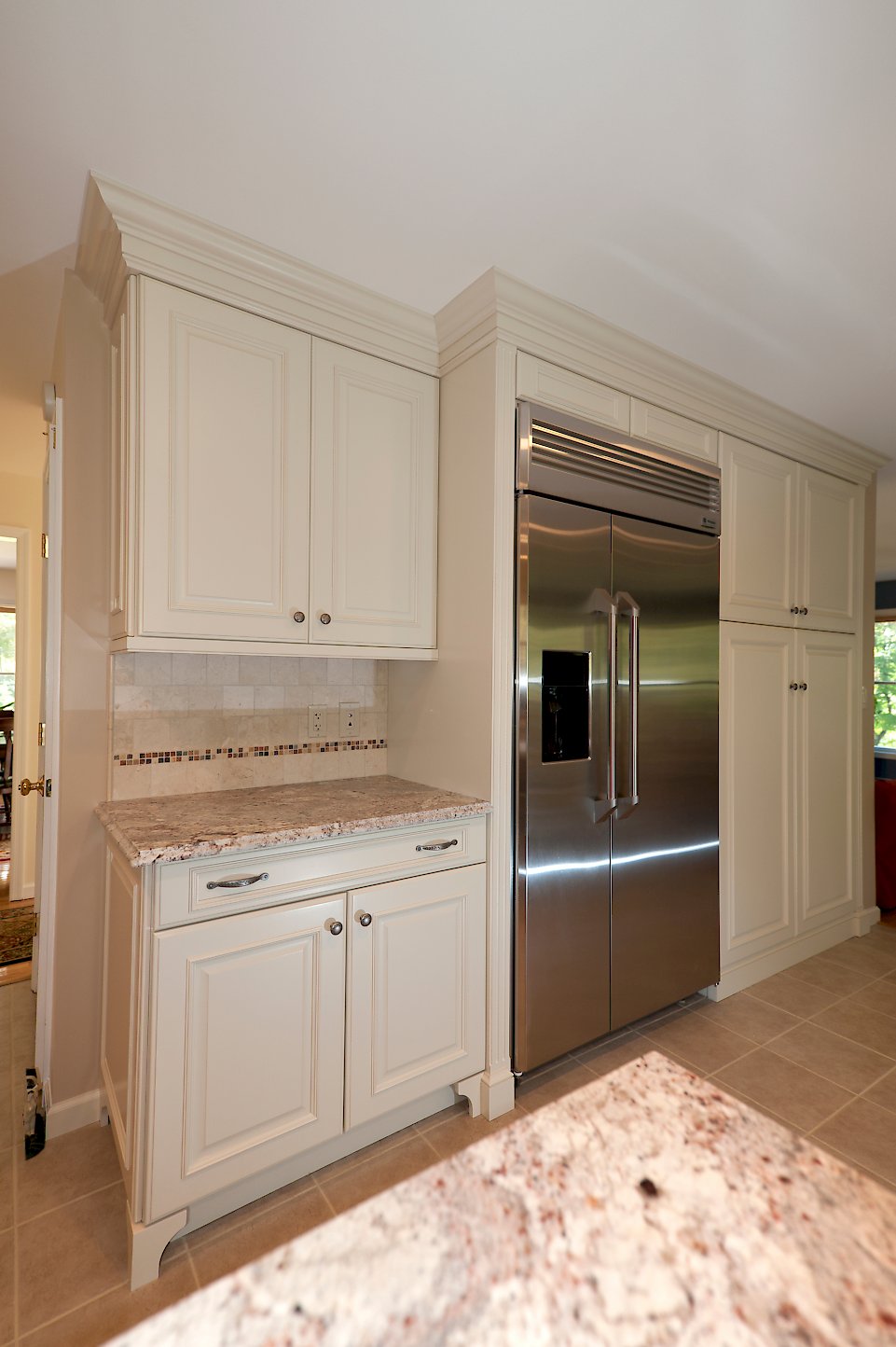 A stainless steel refrigerator with more cabinetry on the opposite wall.